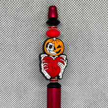 Load image into Gallery viewer, beadable pen Pumpkin character with skeleton hands holding a heart, on a red and black background