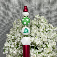 Load image into Gallery viewer, Decorative hair stick with green and white polka dot beads and red accents on a floral background
