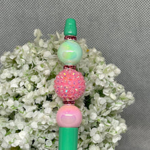 Load image into Gallery viewer, Decorative beadable pen with green, pink, and white beads on a floral background

