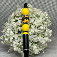 Load image into Gallery viewer, Black and yellow beaded object on a bed of white flowers
