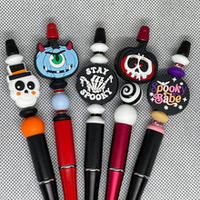 Load image into Gallery viewer, Set of Halloween-themed lip balms with colorful designs on a textured gray background
