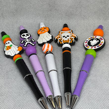 Load image into Gallery viewer, Set of Halloween-themed pens with decorative caps on a textured gray background
