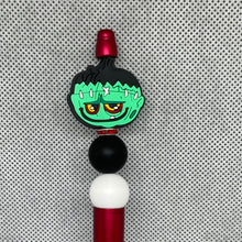 Load image into Gallery viewer, Character-shaped pen top with green face, red hair, black ball, and white sphere on a textured gray background
