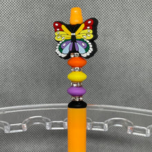 Load image into Gallery viewer, Colorful butterfly-shaped pen top on a transparent stand with a gray textured background
