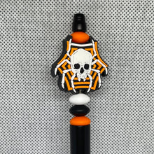 Load image into Gallery viewer, Decorative pen top with skull and spider web design on a textured gray background
