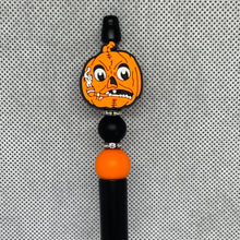 Load image into Gallery viewer, Pumpkin character charm on a black and orange bead against a gray textured background
