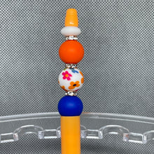 Load image into Gallery viewer, Decorative pencil top with colorful beads on a clear stand against a textured gray background
