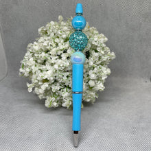 Load image into Gallery viewer, Blue pen with decorative top on a gray surface with white flowers
