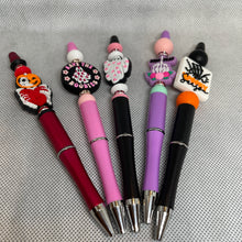Load image into Gallery viewer, Five decorative pens with unique designs on a textured gray background
