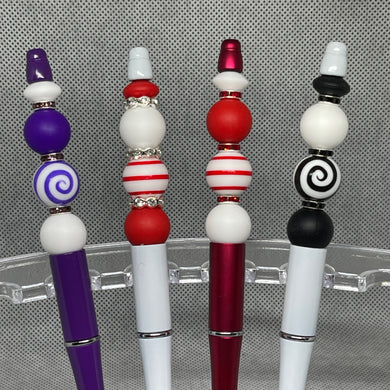 Four decorative pens with colorful bead accents on a gray background