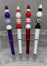 Load image into Gallery viewer, Four decorative pens with colorful bead accents on a clear stand.
